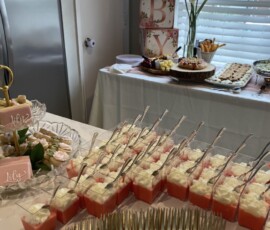 Screenshot Table with desserts, gold forks, and a "BABY" block decoration in the background at a baby shower.