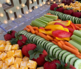 Tray with cubed cheese, strawberries, assorted vegetables, and a lit-up "GRAD 2023" sign in the background.