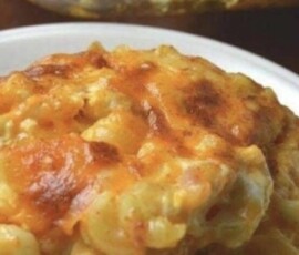 A serving of baked macaroni and cheese with a golden, melted cheese topping on a white plate.